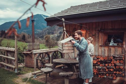 a man and a woman standing outside of a wooden building at Chalet trappeur in Le Biot