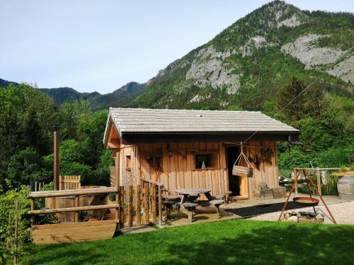 a small wooden cabin with a table and a swing at Chalet trappeur in Le Biot