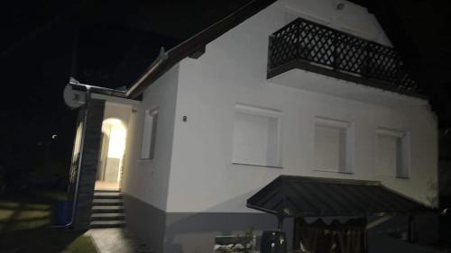 a white building with a staircase and a balcony at Talabér Vendégház in Vonyarcvashegy