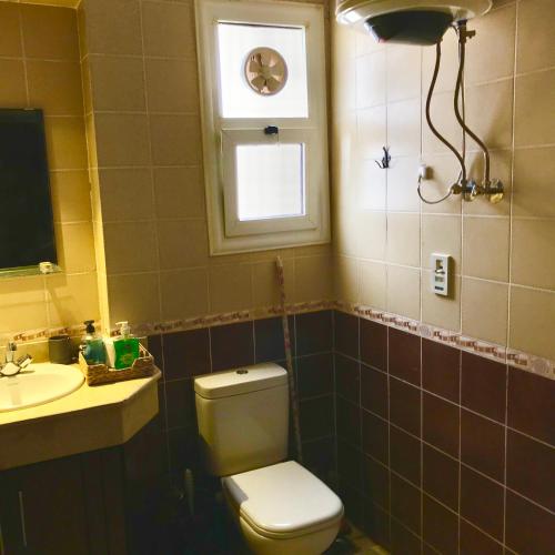 a bathroom with a toilet and a sink and a window at Chalet Marina Wadi Degla Families Only Pool view 2nd floor with Roof 6 adults in Ain Sokhna