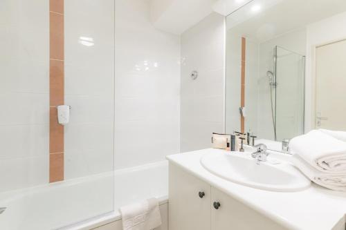uma casa de banho branca com um lavatório e um chuveiro em Appart'City Confort La Ciotat - Côté Port em La Ciotat