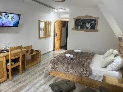 a bedroom with a bed and a desk and a television at Rustic Inn River in Plitvička Jezera