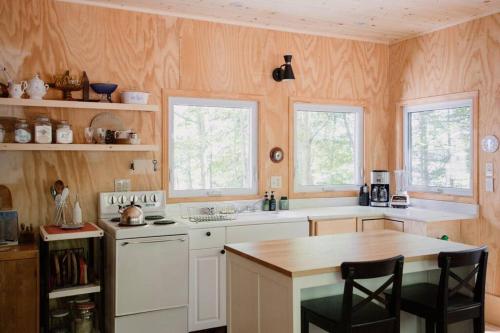 uma cozinha com electrodomésticos brancos e duas janelas em The Dance Hall Cottage on Charleston Lake em Delta