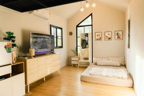 een grote woonkamer met een tv en een bank bij Cana​ Garden​ House​ โฮมสเตย์​ in Ban Khok