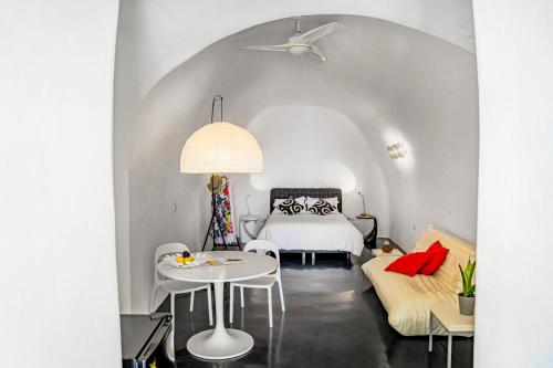 a bedroom with a white bed and a table and chairs at Sensyo Traditional Caves in Firostefani