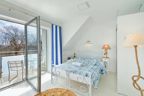 a white bedroom with a bed and a balcony at 3 Kolory ADULTS ONLY in Rogowo