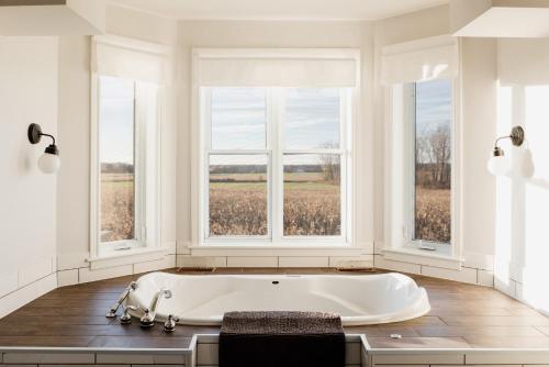 a white bath tub in a room with windows at Fox Lane - Prince Edward County Farmhouse in Picton