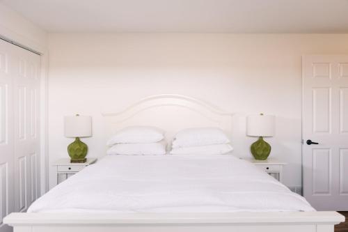ein weißes Schlafzimmer mit einem großen weißen Bett mit zwei Lampen in der Unterkunft Fox Lane - Prince Edward County Farmhouse in Picton