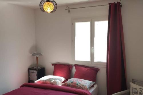a bedroom with a bed with red pillows and a window at Appartement 3 pièces avec terrasse au soleil in Le Thoronet