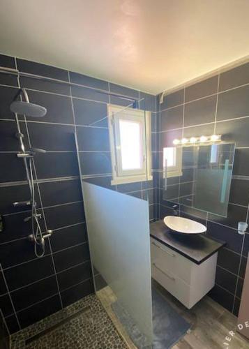 La salle de bains est pourvue de carrelage bleu, d'un lavabo et d'un miroir. dans l'établissement Magnifique villa moderne Jacuzzi 4 chambres 3 salle de bain proche plage centre ville activité, au Barcarès