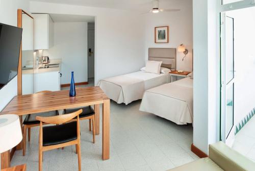 a hotel room with two beds and a table and a desk at Parque Santiago IV Official in Playa de las Americas