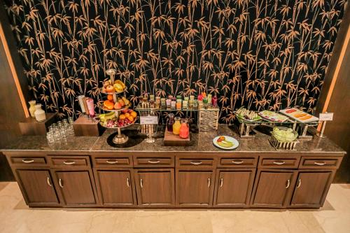 ラクナウにあるRegenta Central Lucknow by Royal Orchid Hotels Limitedのカウンターの上に食べ物と飲み物を用意しています。