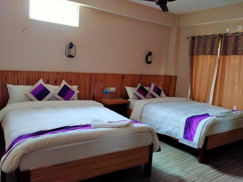 a bedroom with two beds and a window at HOTEL CROWN HORIZON in Sauraha