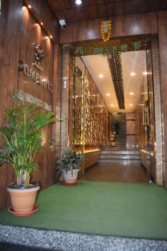 a lobby with potted plants on a green carpet at Hotel UR Comforts Jayanagar in Bangalore