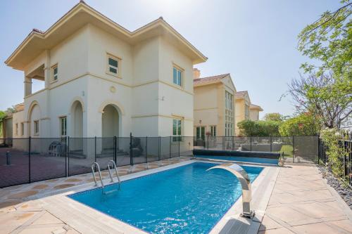 a home with a swimming pool in front of a house at Jumeirah Islands Private Pool Villa in Dubai