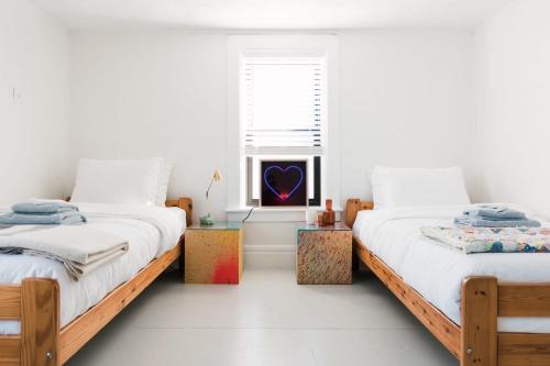 two beds in a white room with a window at Hart House a fresh 3 bedroom century home in Cherry Valley