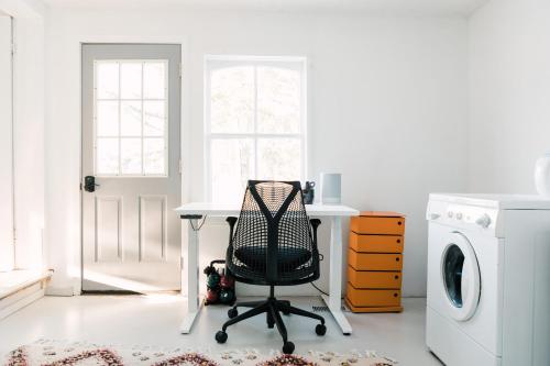 a desk with a chair in a room with a washing machine at Hart House a fresh 3 bedroom century home in Cherry Valley