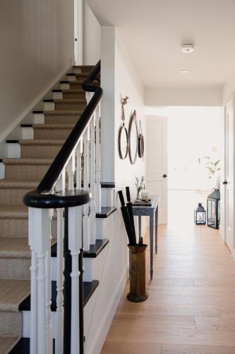 a staircase with black and white railings in a house at The Hull House - Lake Ontario Waterfront w Sauna in Wellington