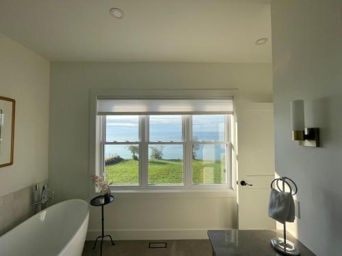 a bathroom with a bath tub and a window at The Hull House - Lake Ontario Waterfront w Sauna in Wellington