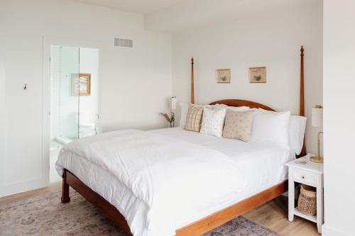 a white bedroom with a large bed with white sheets at The Hull House - Lake Ontario Waterfront w Sauna in Wellington