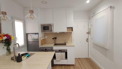 a white kitchen with a sink and a refrigerator at Atocha Suite in Madrid