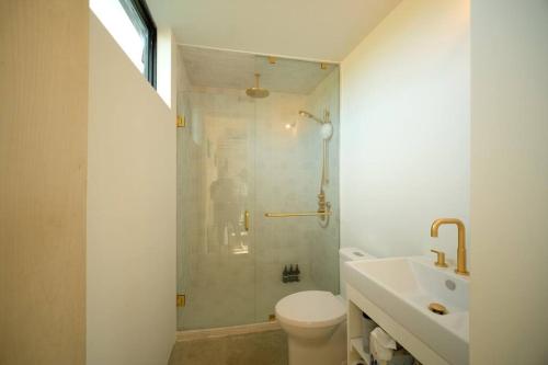 a bathroom with a shower and a toilet and a sink at Hygge House Cozy Boutique Guest House in Hillier