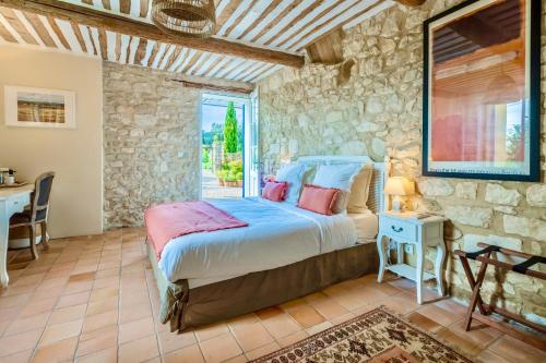 a bedroom with a bed and a stone wall at Bastide Saint-Didier in Saint-Didier