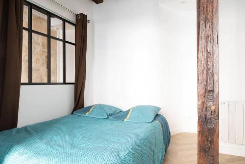 - un lit avec des draps bleus dans une chambre avec une fenêtre dans l'établissement Appartement 2 chambres Lyonnais, à Paris