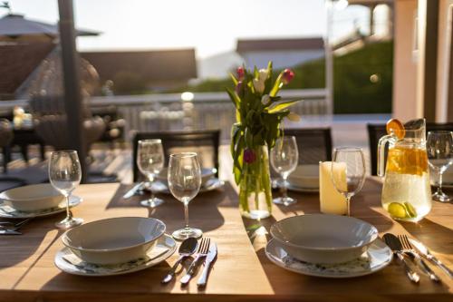 a wooden table with plates and glasses and a vase of flowers at Beautiful Holiday Home "Villa Relax Oasis" in Trogir