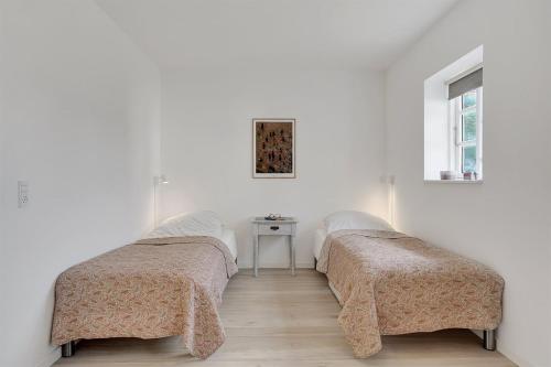 two beds in a white room with a table at GIMLEretreat in Marielyst
