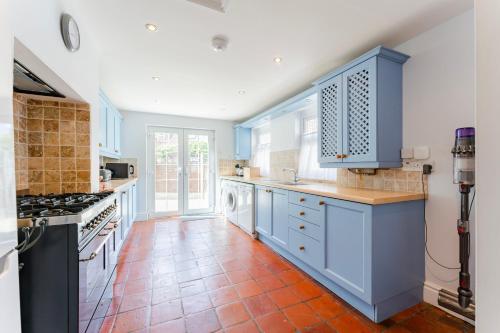 a kitchen with blue cabinets and a red tile floor at Barnacle Nook - Norfolk Cottage Agency in Sheringham