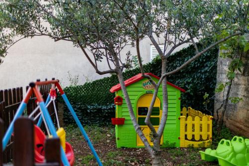 a green toy house and a tree in a yard at Beautiful Holiday Home "Villa Relax Oasis" in Trogir