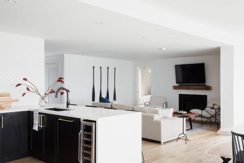 a kitchen with black cabinets and a living room at Wellers Landing - Prince Edward County Lakehouse in Carrying Place
