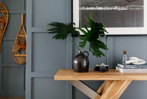 a plant in a black vase on a wooden table at Wellers Landing - Prince Edward County Lakehouse in Carrying Place