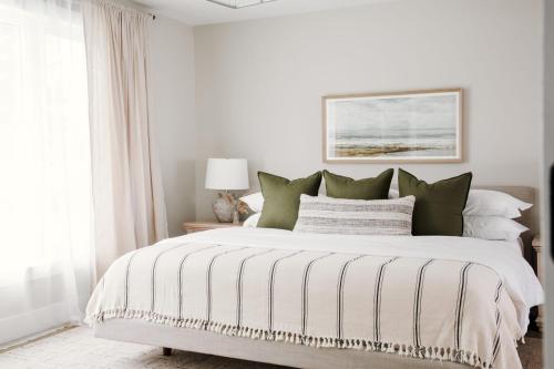 1 dormitorio con 1 cama grande con almohadas verdes en Wellers Landing - Prince Edward County Lakehouse, en Carrying Place