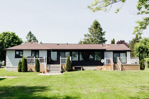 a home with a large yard with a house at Wellers Landing - Prince Edward County Lakehouse in Carrying Place