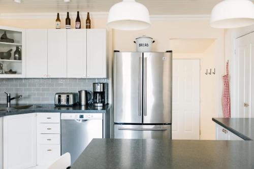 een keuken met een roestvrijstalen koelkast en witte kasten bij Watson House - Century Home near Sandbanks in Cherry Valley