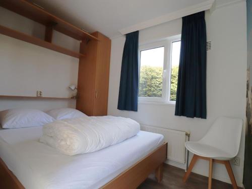 een slaapkamer met een bed met een raam en een stoel bij Modern chalet in Grou with a spacious garden in a beautiful location in Grou