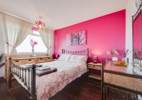 Un dormitorio con una pared rosa y una cama en 7 The Bungalows, en Hinderwell