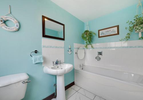 y baño con paredes azules, lavabo y bañera. en 7 The Bungalows, en Hinderwell