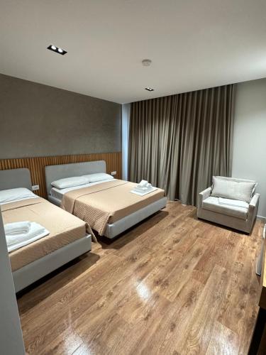 a bedroom with two beds and a chair at Hotel Ajden by Mira Mare in Ksamil