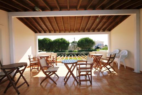 a patio with wooden tables and chairs and a large window at NIRVANA in Plati