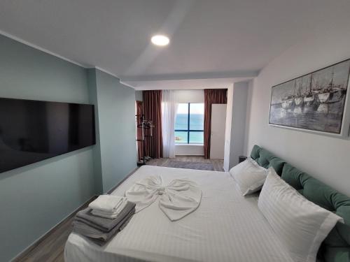 ein Schlafzimmer mit einem weißen Bett mit einer Schleife darauf in der Unterkunft Olimp Sea View Apartments Etajul 10 in Olimp