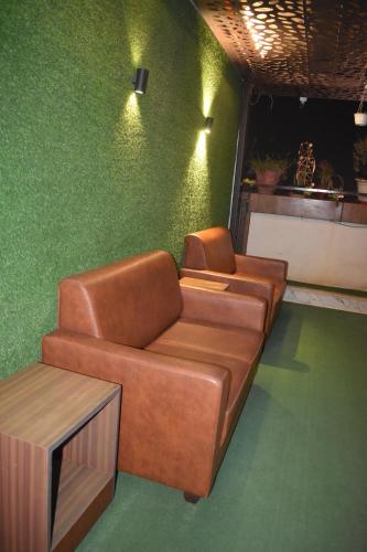 a living room with a leather couch and a table at Hotel UR Comforts Jayanagar in Bengaluru