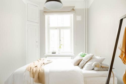 - une chambre blanche avec un lit blanc et une fenêtre dans l'établissement Roost Korkea 8, à Helsinki