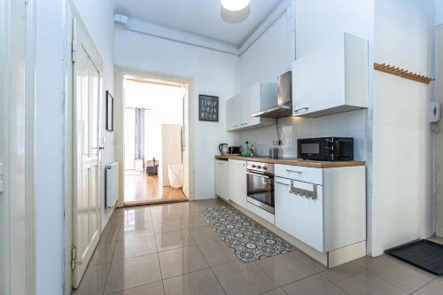 a kitchen with white cabinets and a tile floor at Vltava Apartments Prague 7 in Prague