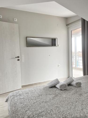 a white bedroom with a bed with a window at Delia Apartments in Pefkohori