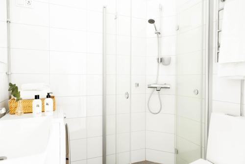 uma casa de banho branca com um chuveiro com uma porta de vidro em Roost Korkea 8 em Helsínquia