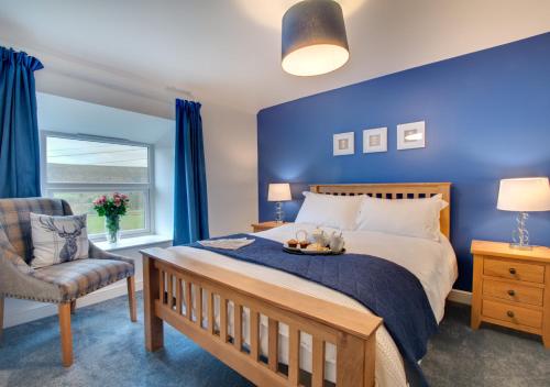 1 dormitorio azul con 1 cama y 1 silla en Woodhead Farm Cottage, en Danby