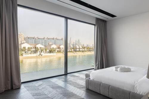 a bedroom with a large window with a view of the beach at Palm Jumeirah Paradise - 5BR Villa - Infinity Pool in Dubai
